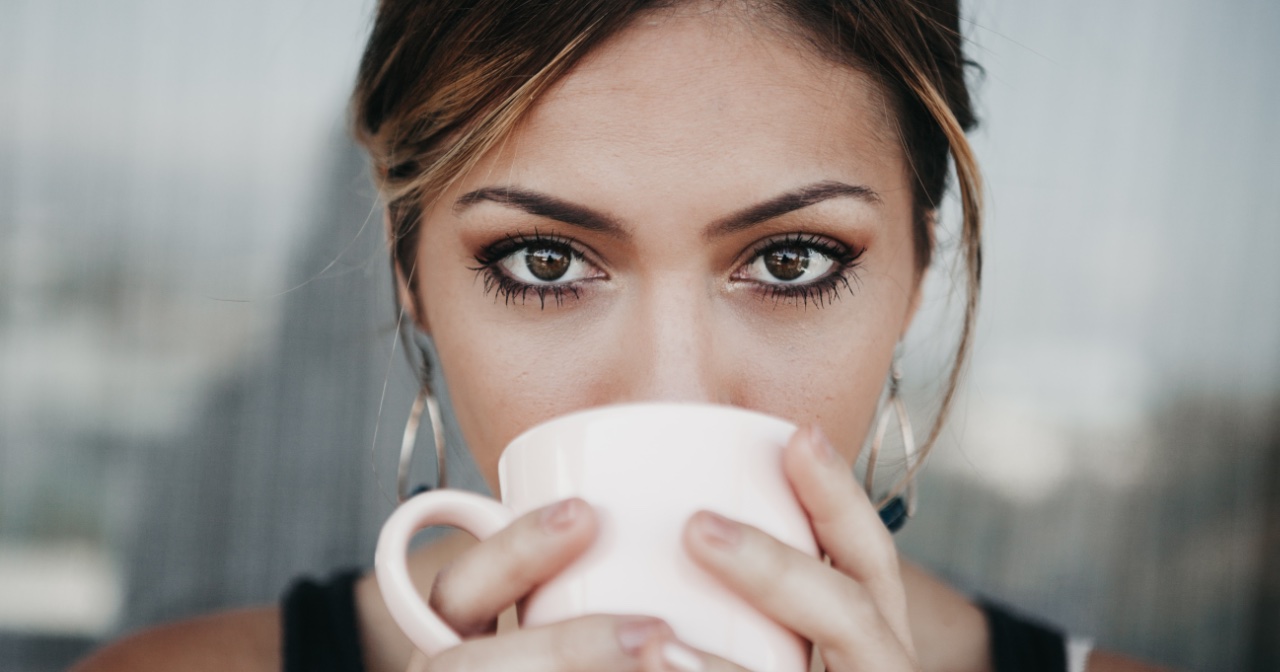 Woman holding coffee cup in front of her mouth
