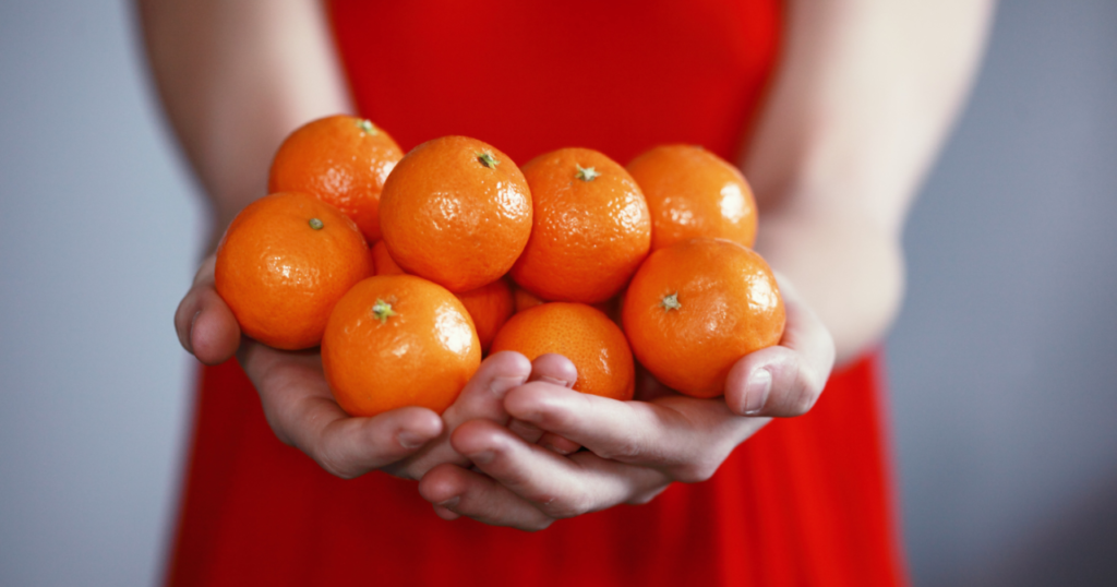 Woman in red dress holding tangerines in front of her