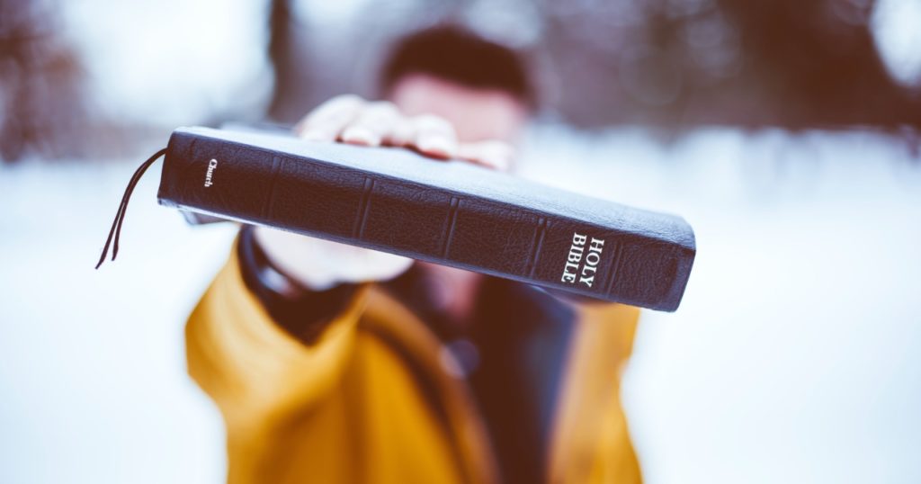 Man holding Bible out towards camera