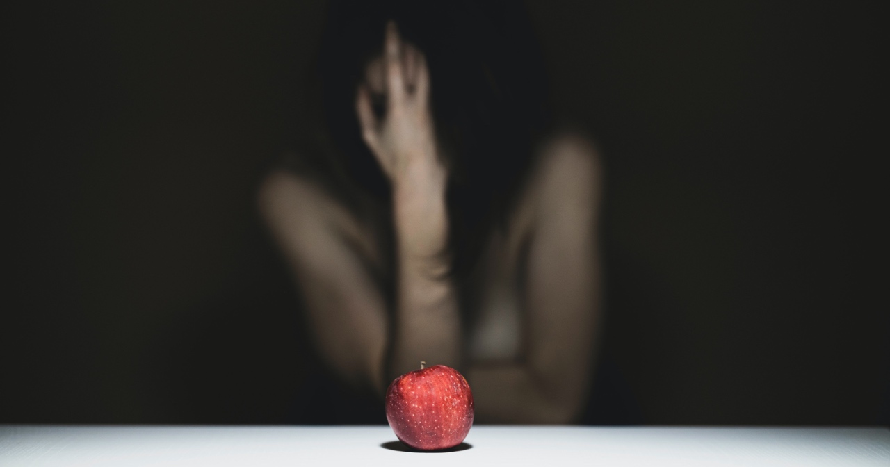 Woman holding her head in her hand in front of an apple on the table