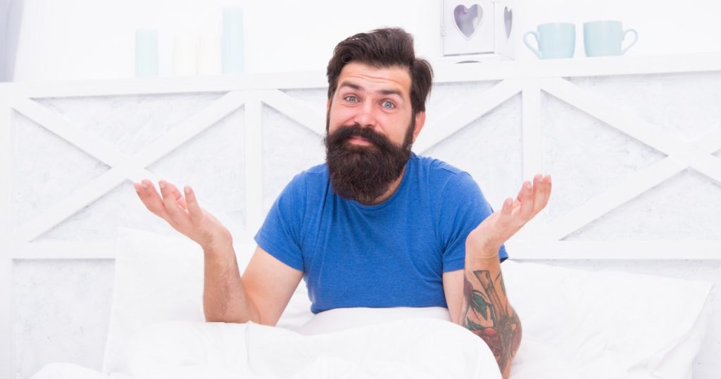 Man in bed with confused look on his face