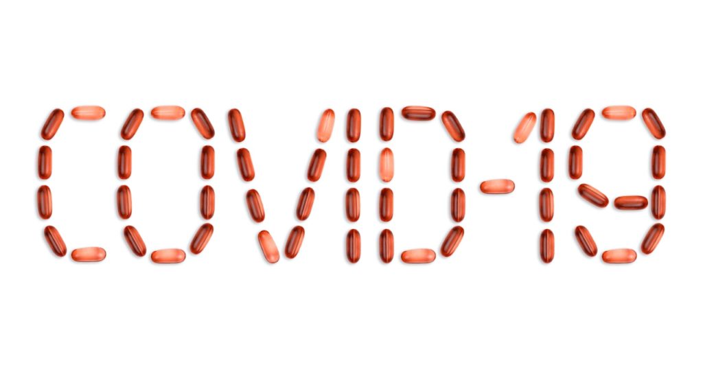 Supplement pills arranged to spell COVID-19