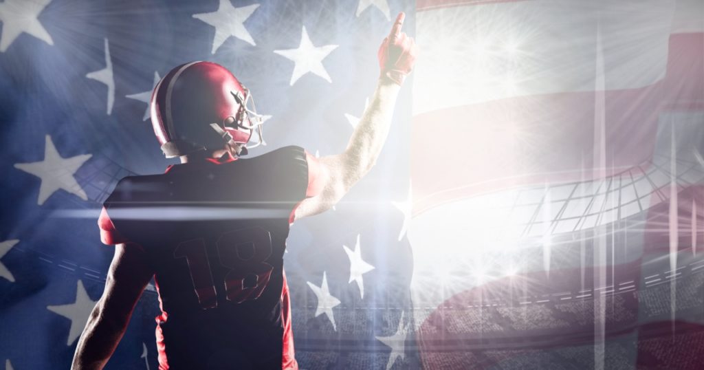 Football player with his finger to the sky and American flag in the background