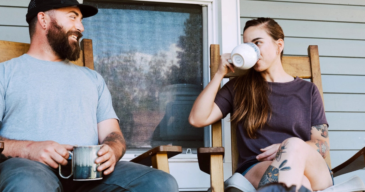 Man and woman drinking coffee on front porch
